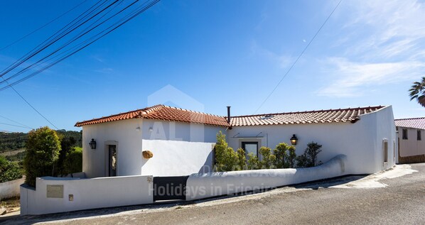 Un bâtiment d ’un seul étage, doté d’un toit en tuiles, d’un petit porche et d’un mur extérieur peint en blanc.