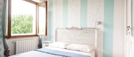 A bedroom with a bed, a window, and striped walls.