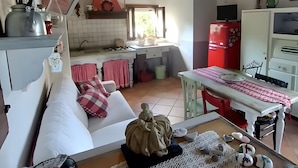 A cozy living room with a sofa, a table with decorative items, and a view into the kitchen.