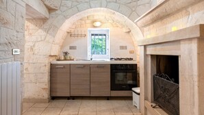 Una cocina con paredes de piedra, una ventana, horno empotrado y chimenea.
