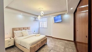 A bedroom with a bed, bedside table, and a TV mounted on the wall. - Luxury & Location, Beautiful & Spacious Apt in Altamira (Caracas)
