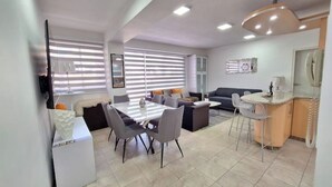 A modern living room with a dining area, a sofa, a TV, and a kitchen area with a bar. - Luxury & Location, Beautiful Apartment in Los2Caminos-Boleita (Caracas)