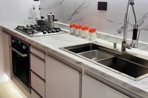 A modern kitchen with a stainless steel sink, a gas stove, and a built-in oven.