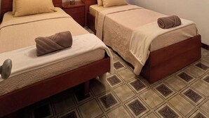 A hotel room with two beds, each with a brown headboard and a beige blanket.