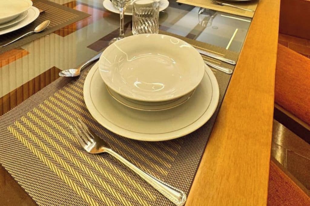 A dining table set with plates, cutlery, and a glass.