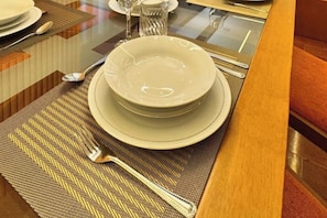 A dining table set with plates, cutlery, and a glass.