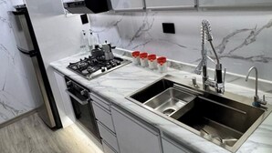 Una cocina moderna con estufa a gas, pileta de acero inoxidable y salpicadero de mármol.
