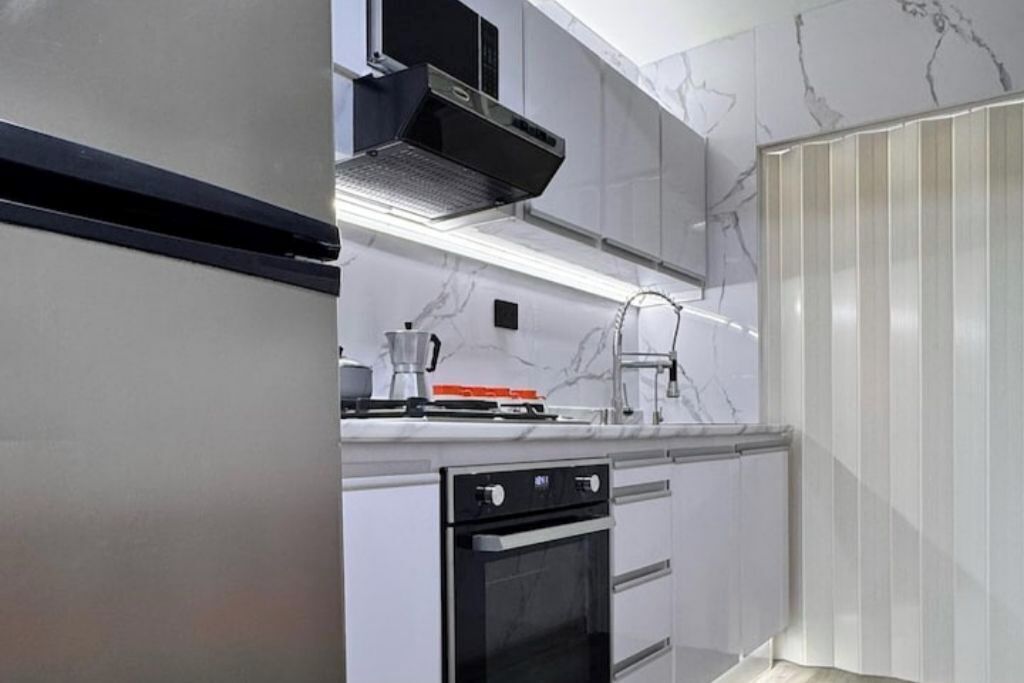 A modern kitchen with white cabinets, a black oven, and a stainless steel range hood.