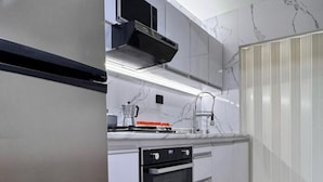 A modern kitchen with white cabinets, a black oven, and a stainless steel range hood.