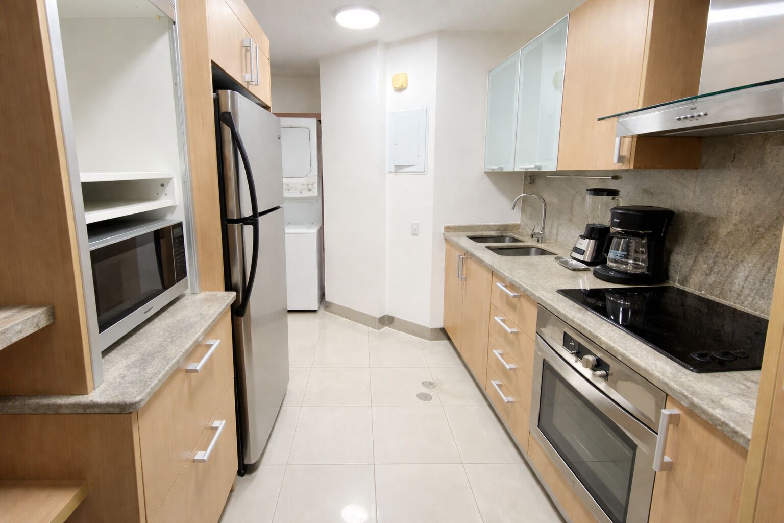 A modern kitchen with stainless steel appliances, wooden cabinets, and a granite countertop.