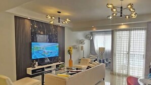 Ein modernes Wohnzimmer mit einem Flachbildfernseher, einer Couch, einem Couchtisch und einem Essbereich mit einem roten Sessel.