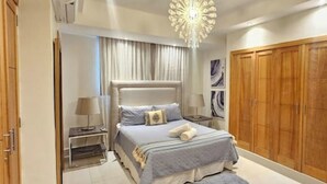 Ein Schlafzimmer mit einem großen Bett, Nachttischen, einem Kleiderschrank und einer Chandelier.