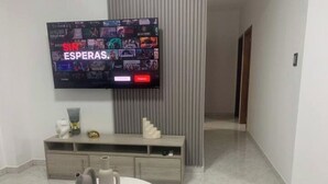 Ein modernes Wohnzimmer mit einem an der Wand befestigten Flachbildfernseher, der eine Auswahl an Filmen zeigt.