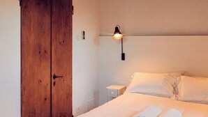 A bedroom with a wooden wardrobe, a bed with white linens, and a wall-mounted light fixture. - Logge, Life and sights of Tuscan Hills, 15 minutes from Florence (Toscana)