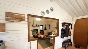 Ein Zimmer mit Holzboden, einem Spiegel, einer Hängelampe, einem Sofa und einer Gitarre.