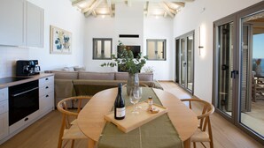 Una cucina moderna con zona pranzo, una macchina da caffè, una bottiglia di vino e un bicchiere su un vassoio.