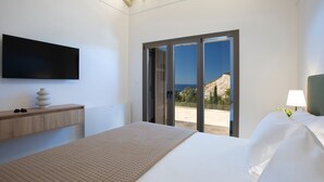 Camera d'albergo moderna con un letto, una TV a schermo piatto, un comodino in legno, una lampada e vista sull'esterno.