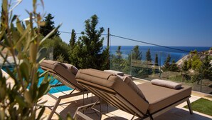Area piscina con sedie a sdraio e vista mare.