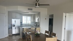 Une cuisine spacieuse dotée d’un îlot central, d’appareils électroménagers modernes et d’un coin repas avec une table et des chaises en bois.