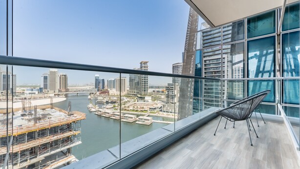 Un balcone con vista sulla città, tra cui grattacieli e un porto turistico.