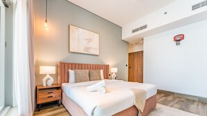 Una camera d'albergo moderna con un letto grande, lampade sui comodini, un'opera d'arte appesa al muro e un canestro da basket.