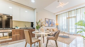 Una cucina moderna con forno integrato, una zona pranzo con tavolo e sedie rotonde, e un soggiorno con divano e tavolino.