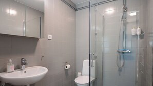 Un baño moderno con ducha acristalada, lavabo blanco y retrete.