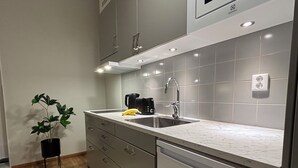 Una cocina moderna con gabinetes grises, un lavamanos de acero inoxidable, una cafetera negra y una planta en maceta.