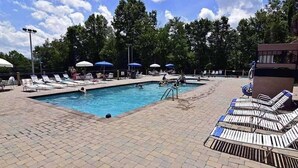Une piscine avec des chaises longues et des parasols.