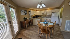 Une cuisine de taille réduite avec des meubles de rangement en bois, une table à manger avec des chaises et un lustre.