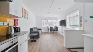Una cocina moderna con hervidor, cafetera y comedor con mesa y sillas.