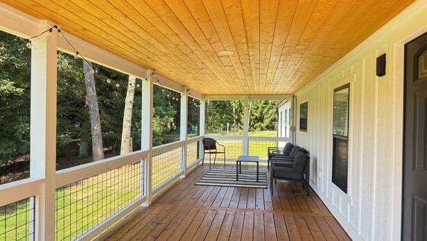 A covered porch with wooden flooring, white railings, and a seating area with a table and chairs. - Nancy James
Charming 2-bedroom retreat with a charming porch in Candler (Candler)