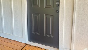 A dark-colored front door with a small window above it, a doorbell, and a welcome mat at the entrance. - Nancy James
Charming 2-bedroom retreat with a charming porch in Candler (Candler)