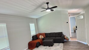 A spacious living room with a sectional sofa, a ceiling fan, and a large window with blinds. - Nancy James
Charming 2-bedroom retreat with a charming porch in Candler (Candler)