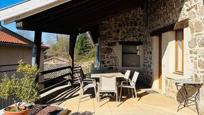 A patio with a stone wall, a covered seating area, and a potted plant.