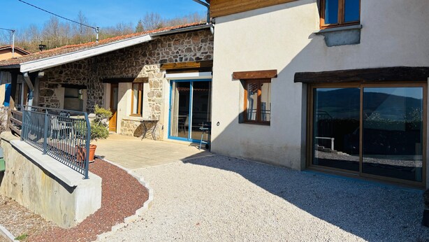 A two-story building with a stone facade, wooden roof, and large sliding glass doors.