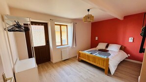 A bedroom with a bed, a radiator, a window, and a door.