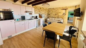 A modern kitchen with pink cabinets, a wooden dining table, and a stone wall.