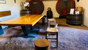 A room with a wooden table, two barrels, a chair, and a shelf with trophies.