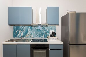 Une cuisine avec des armoires bleues, un réfrigérateur en acier inoxydable, un four encastré et un dosseret en marbre.