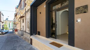 A building with a 'Welcome' mat at the entrance, a plaque on the wall, and a number '154' above the door.
