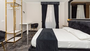 A hotel room with a bed, a desk, a chair, a wardrobe, and a large mirror.