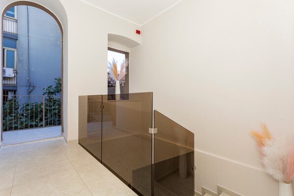 A modern interior with a glass partition, a view to the outside, and a potted plant.