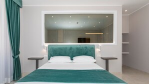 Une chambre à coucher moderne avec un grand lit, une tête de lit de couleur turquoise, deux tables de chevet et un grand miroir au-dessus du lit.