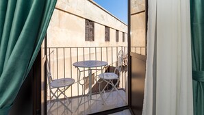 Un balcon avec une table et des chaises, une vue sur un immeuble et des rideaux.