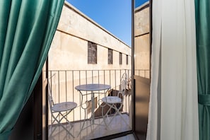 Un balcone con tavolo e sedie, vista su un edificio e tende.