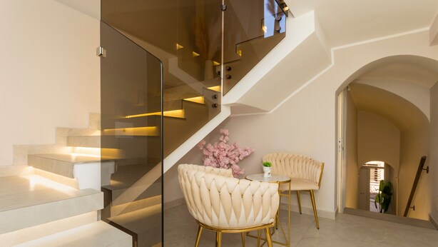 Un intérieur moderne avec un escalier, un coin repas comprenant deux chaises et une petite table.