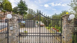 A gated entrance with stone walls and a metal gate, a small building, and a sign indicating a canal. - THE OUTDOOR ROOFTOP HOUSE (Calice Ligure)
