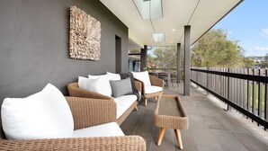 A covered outdoor seating area with wicker furniture and a decorative wall piece. - Surf N Turf - The Grandstand - a romantic couple’s escape near beach, dining & charm in Kiama. (Kiama)