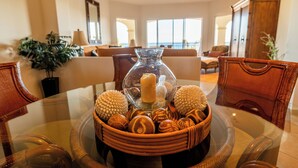 A dining table with a glass centerpiece containing candles and decorative items, surrounded by wicker chairs. - Las Mañanitas LM E3302 (San José del Cabo)